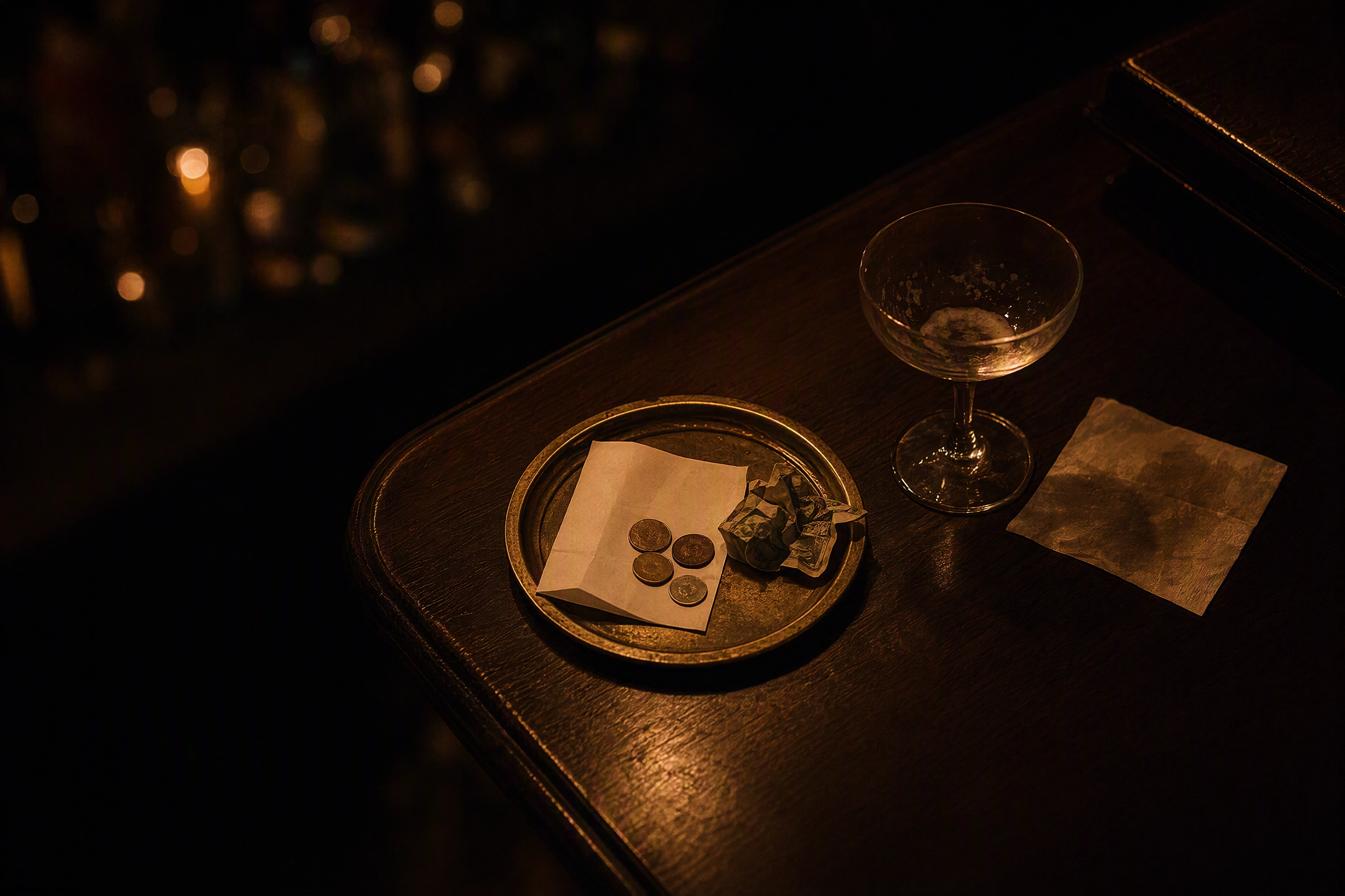 Folded bill and loose coins on a small brass tray beside an empty coupe glass, the margin a win-back discount gives away