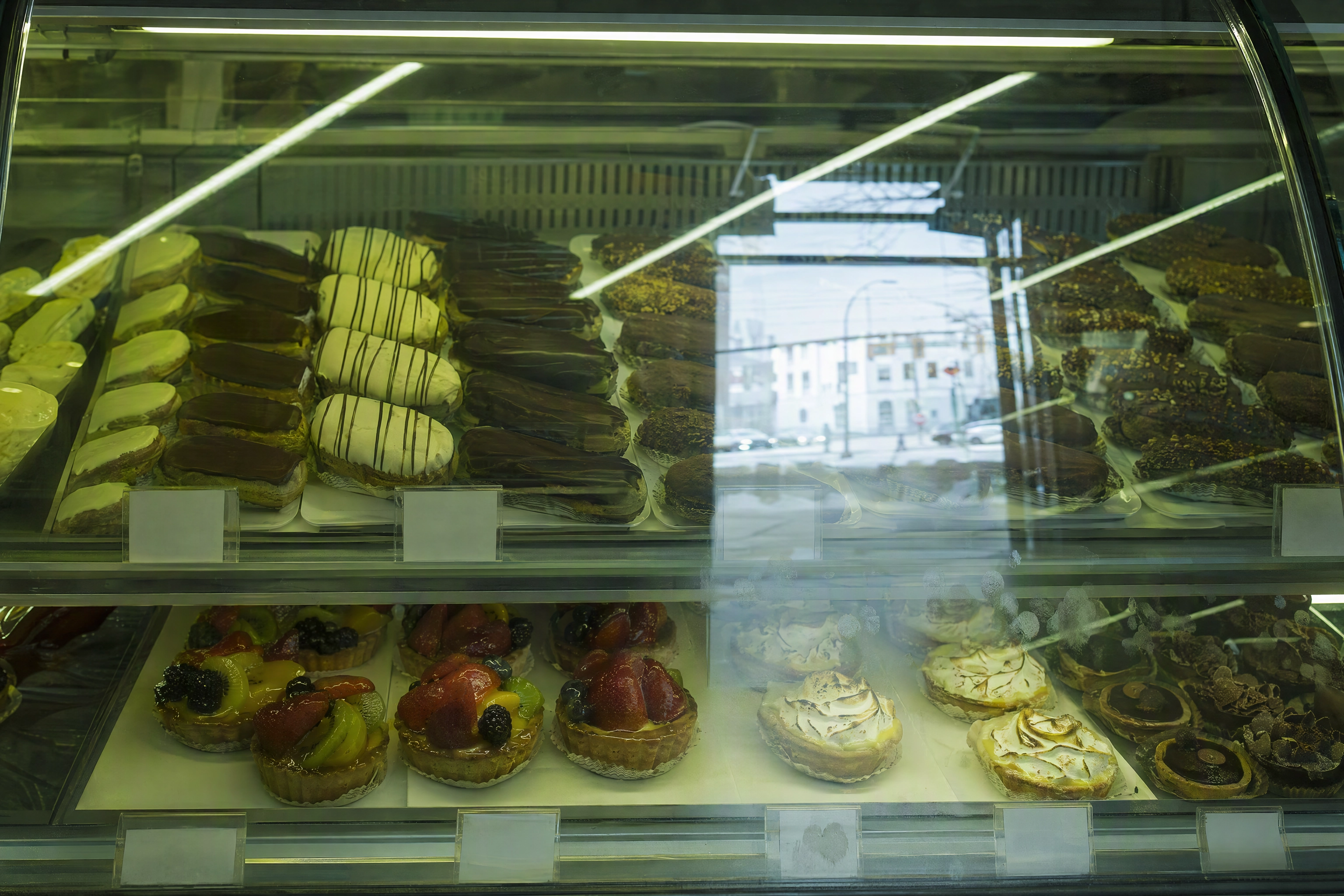 Reflections and glare across bakery display case glass obscuring the pastries behind it