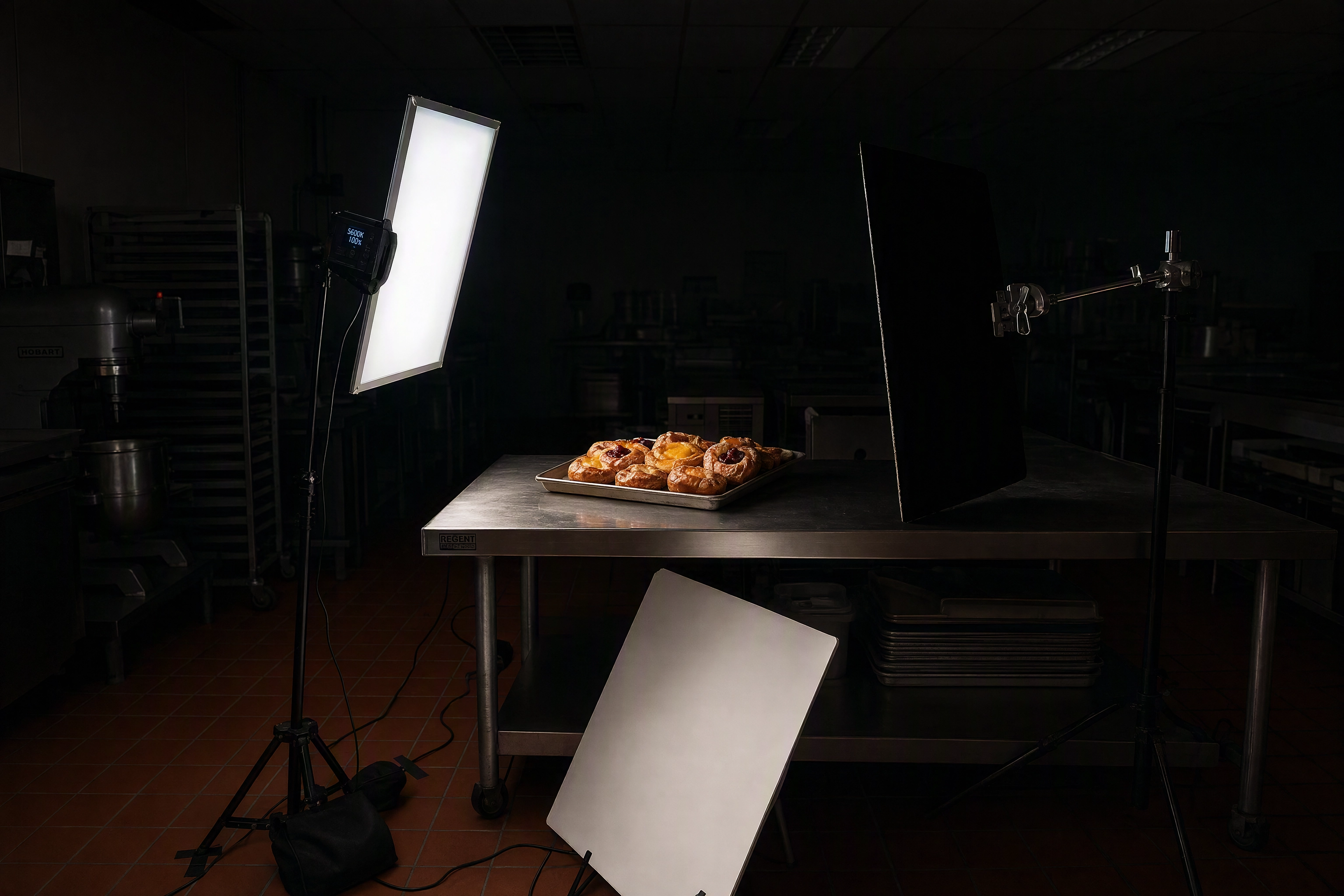One-light bakery photography setup with diffusion panel and black flag lighting a tray of danishes at 5am