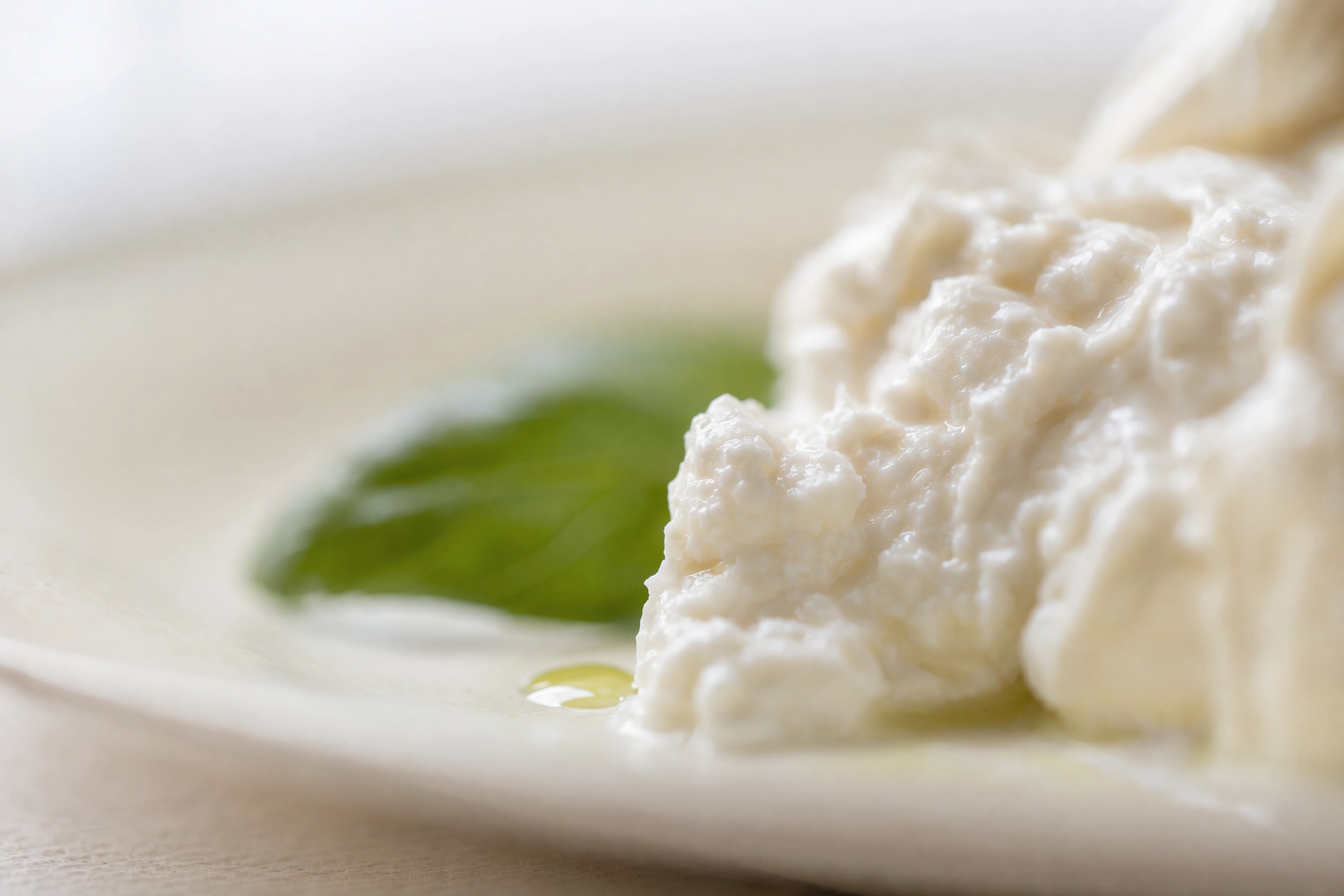 Macro food shot with only a five millimetre sliver of burrata sharp, showing how thin depth of field gets wide open
