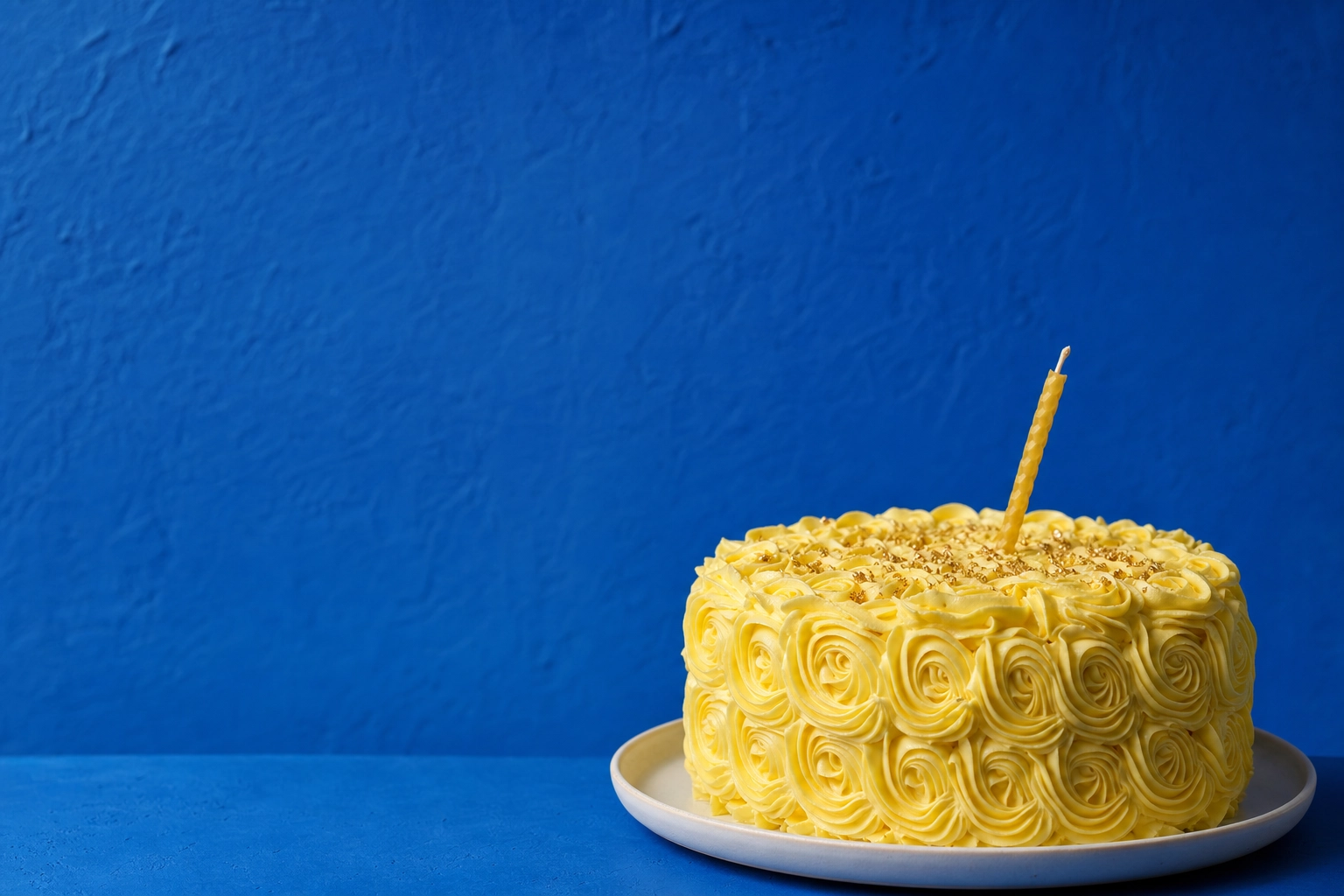 Yellow buttercream rosette birthday cake against cobalt blue background — color-pop cake photography backgrounds
