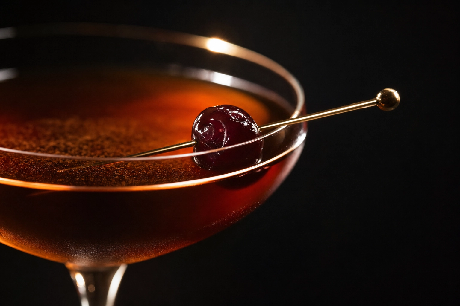 Macro close-up of a Manhattan cocktail showing jewel-tone amber color, backlit rim highlight, and brandied cherry — color editing example