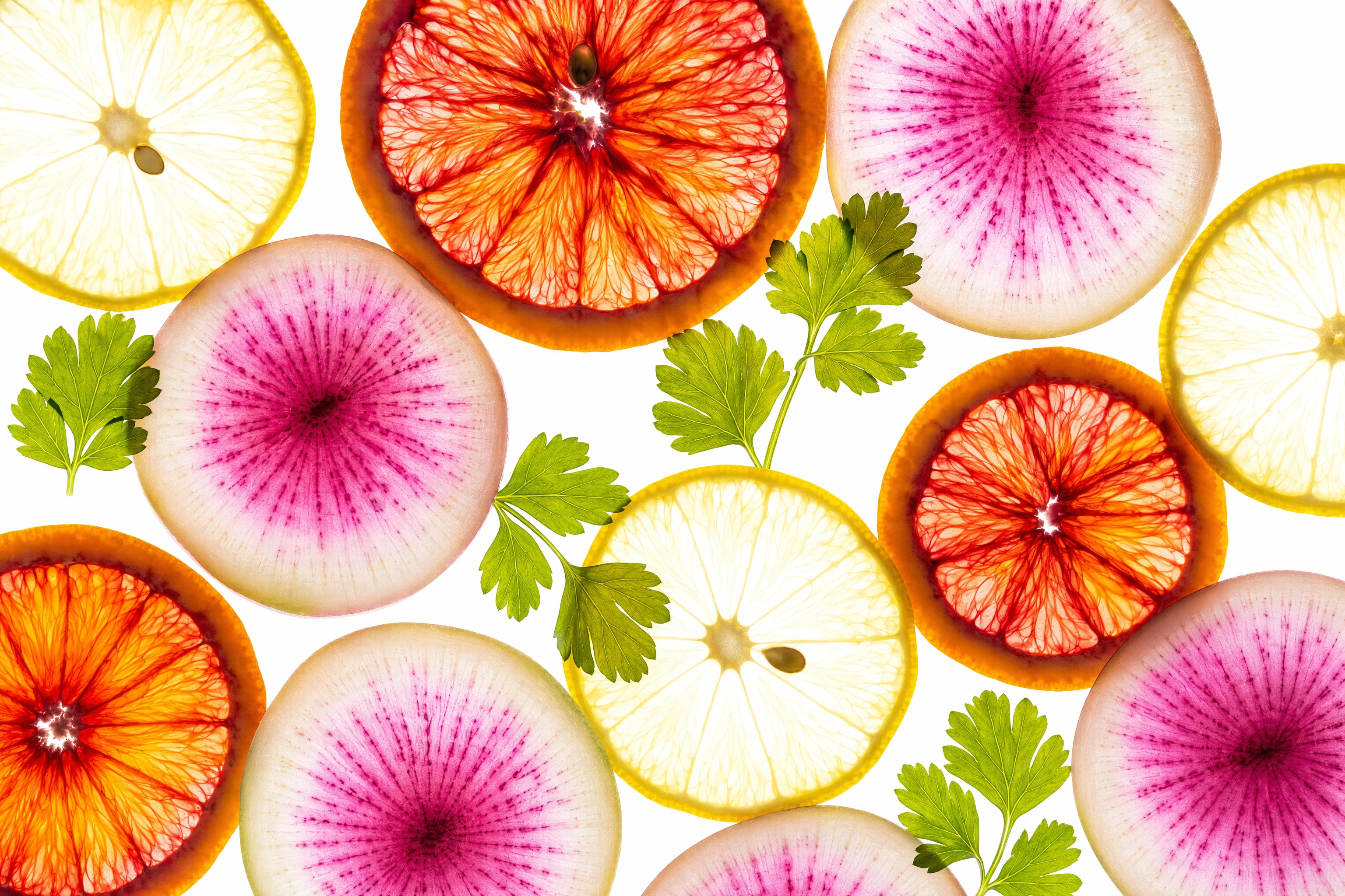 Backlit food photography with translucent blood orange, lemon and radish slices glowing like stained glass on a light table