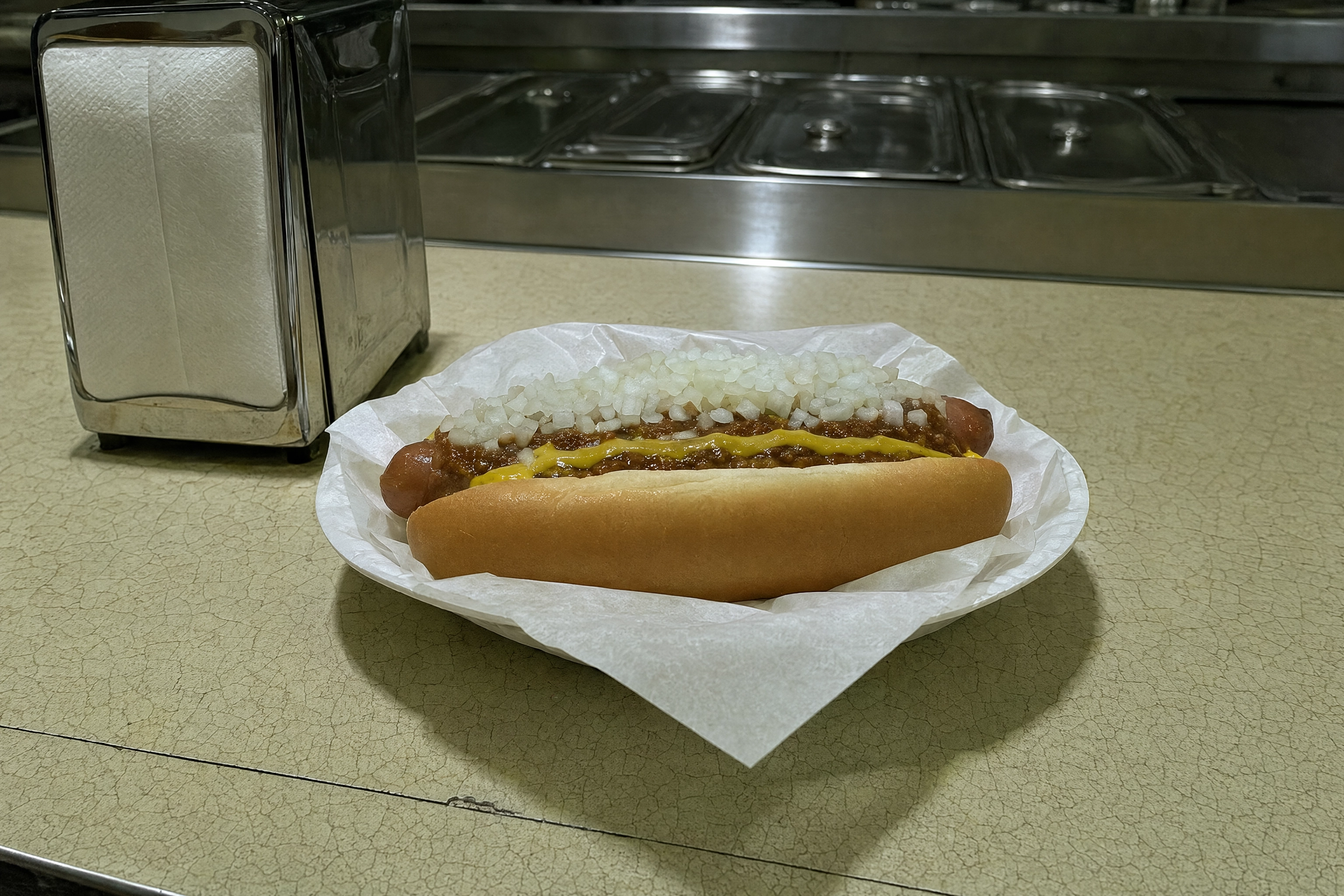 Coney-style chili dog under harsh diner fluorescent light, the brown-on-brown Detroit food photography problem