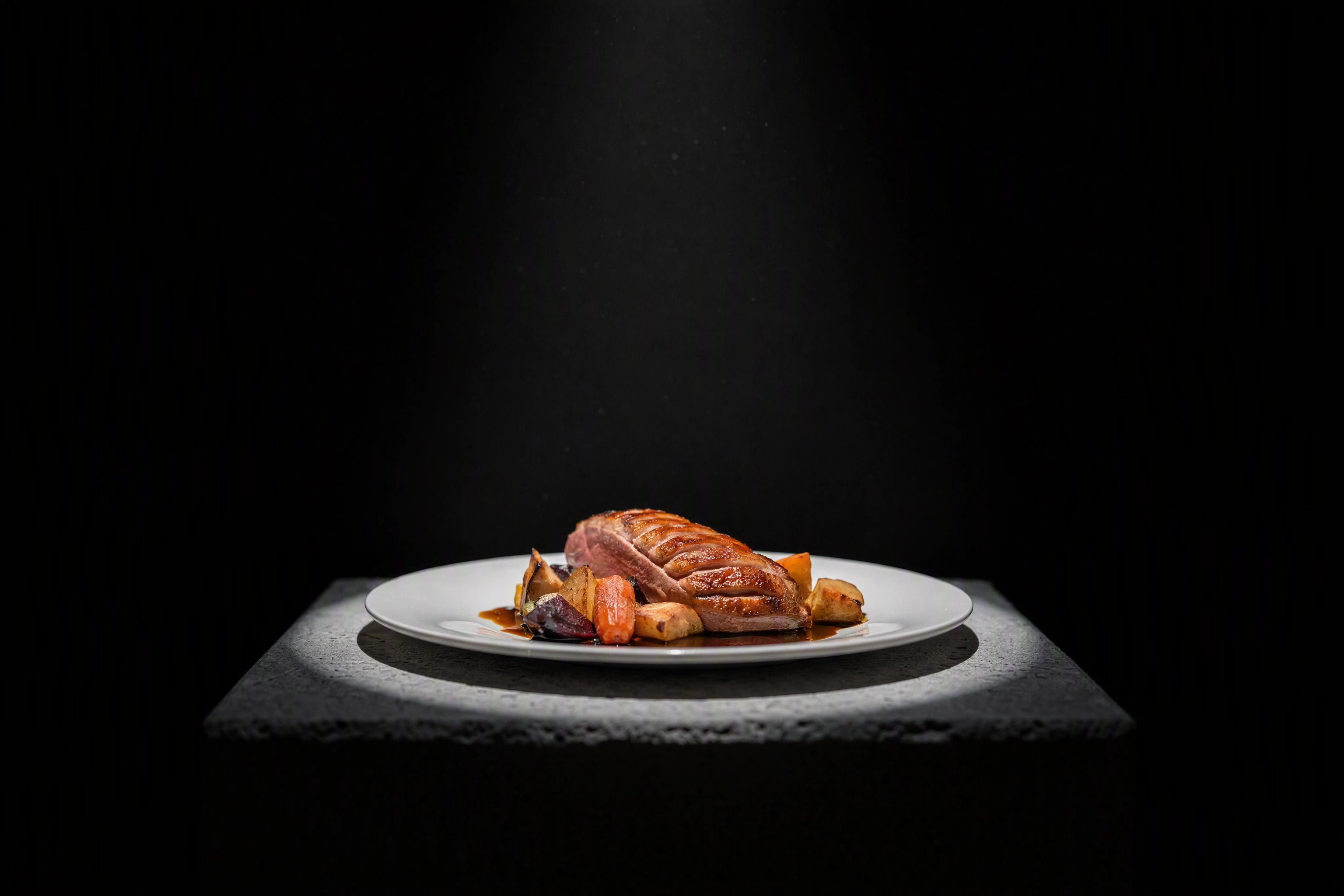 Plated duck dish lit like a museum exhibit on a plinth, a Detroit restaurant kitchen under national scrutiny
