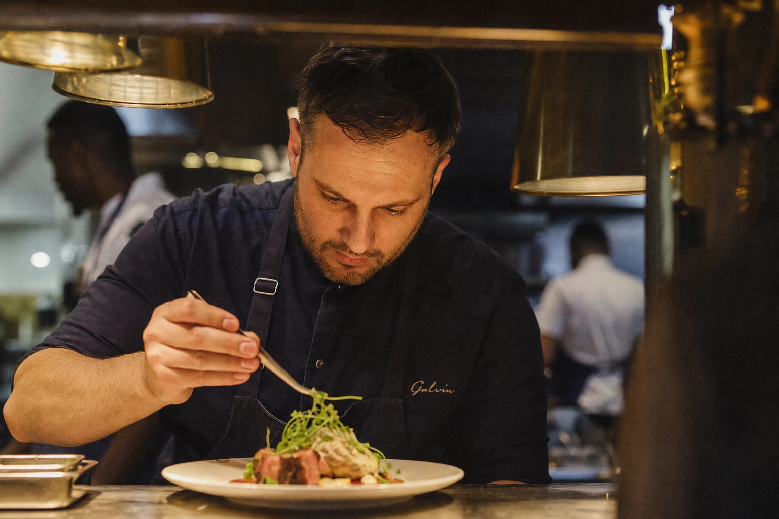 London head chef plating fine dining dish at the pass showing lifestyle photography moments AI cannot replicate