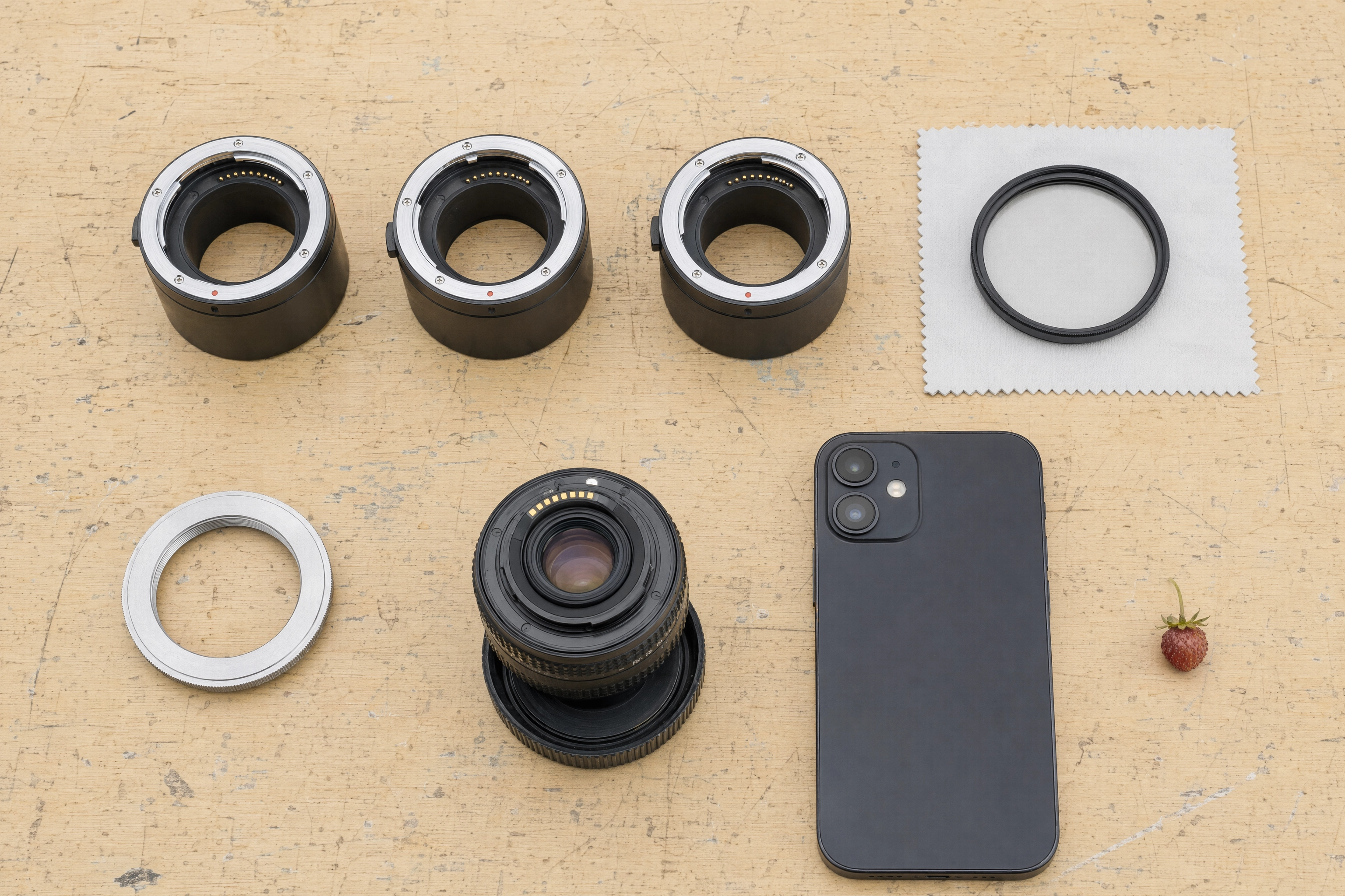 Overhead flat-lay of extension tubes, close-up filter, reversing ring and a phone, budget macro food photography gear