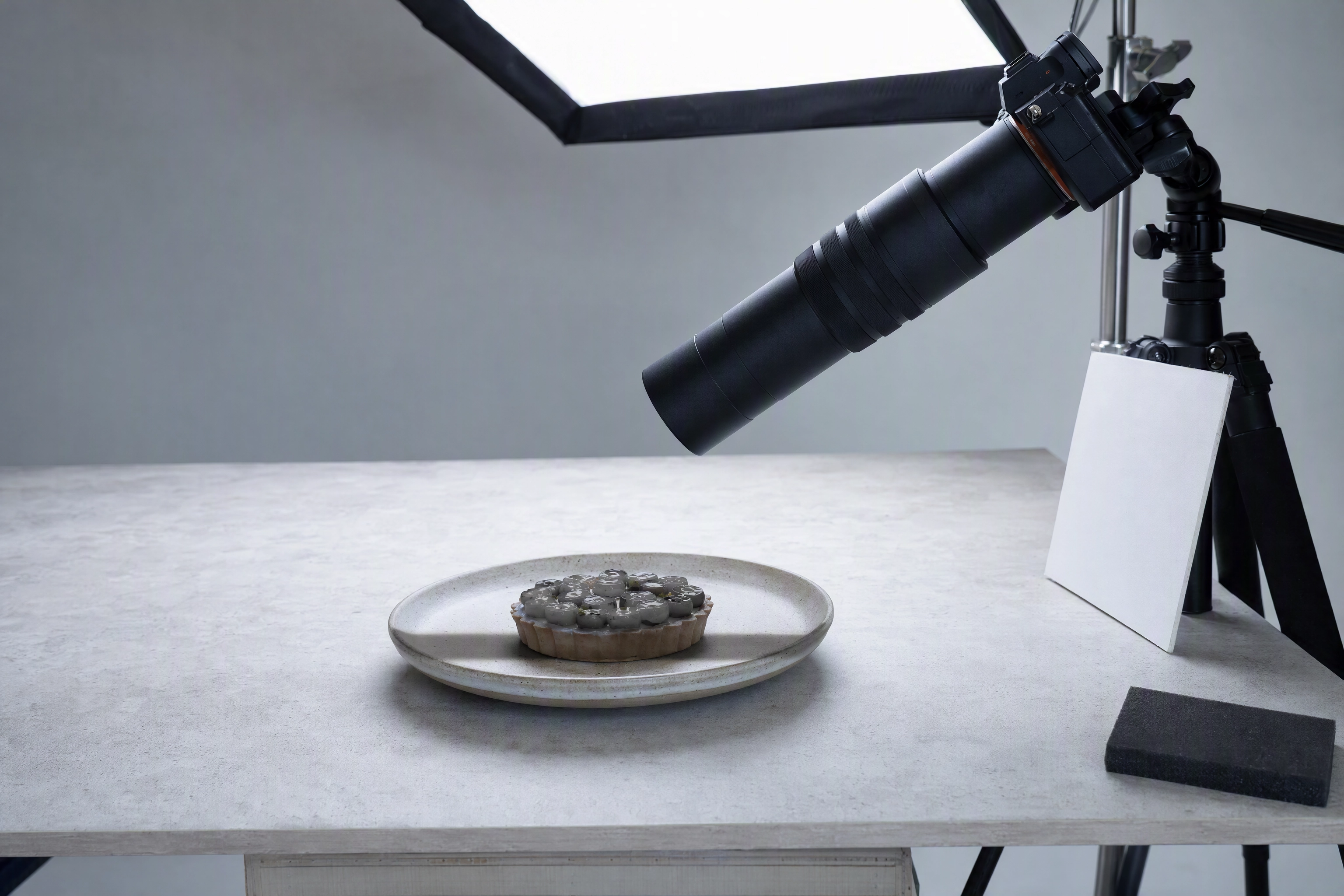 Long macro lens leaning in over a small tart under a softbox, the working distance problem in macro food photography