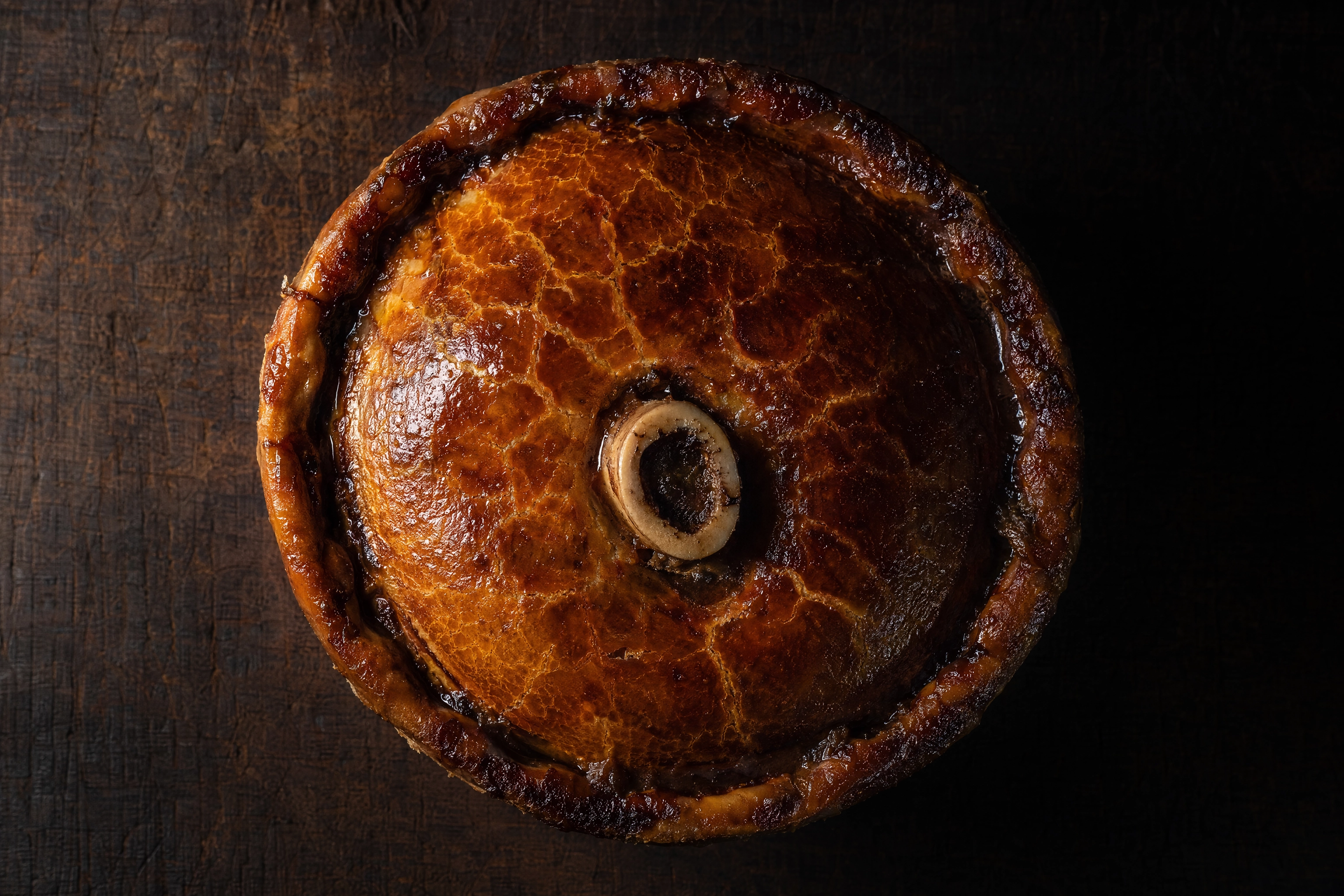 Macro of a burnished deep-filled steak pie with a marrow bone chimney, the hero plate a professional shoot delivers