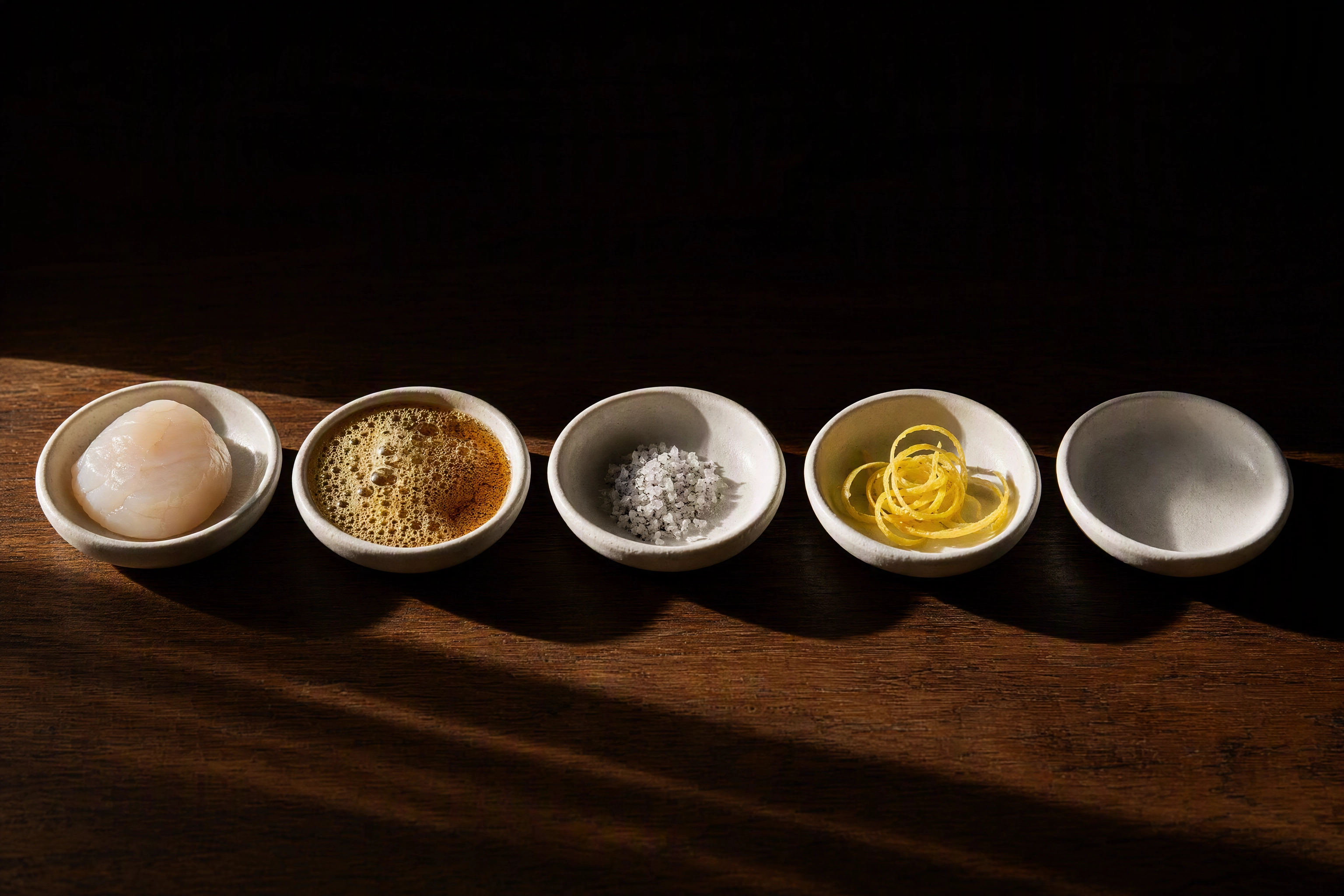 Five small dishes in a row holding one ingredient each with the fifth left empty, the five-slot menu description formula
