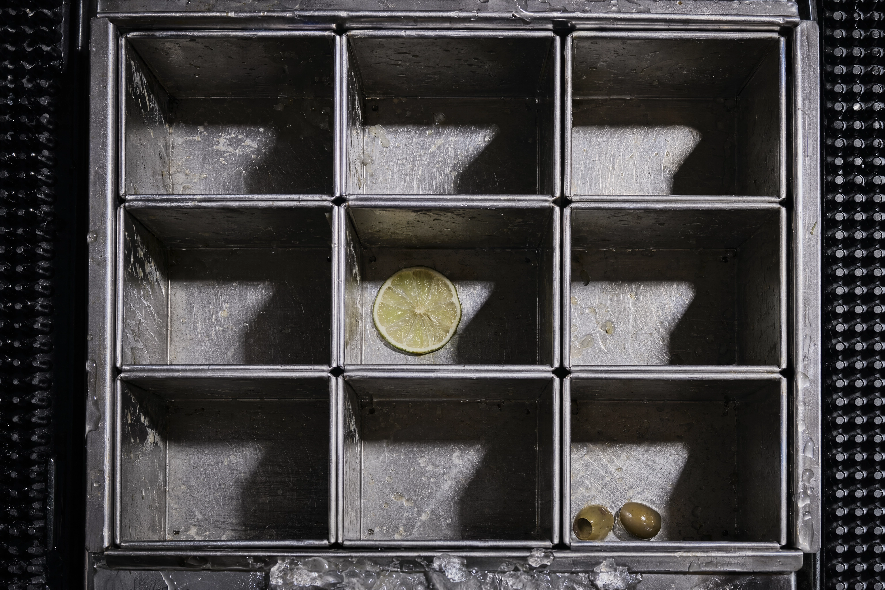 Nearly empty nine-compartment bar garnish caddy at end of service, running out of restaurant content