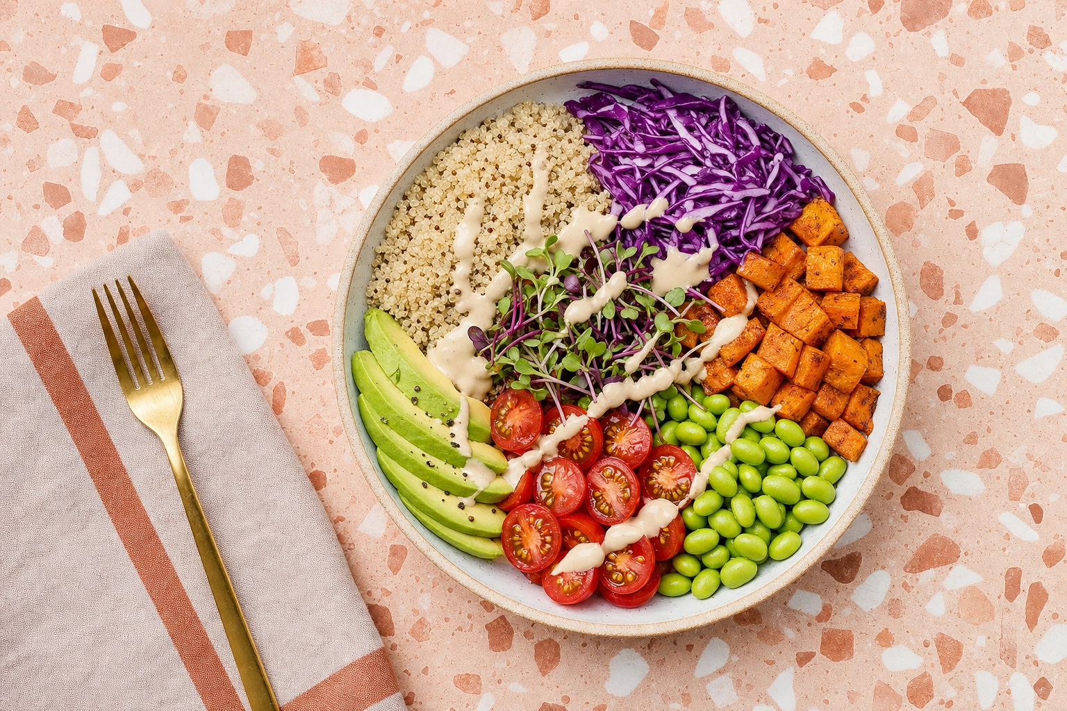 Overhead flat-lay of a colorful grain and greens bowl arranged as a tidy color map on a terracotta terrazzo surface