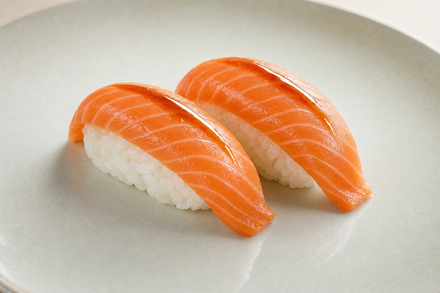Salmon nigiri pair shot at a 45-degree angle showing fish drape and visible rice grains with negative space