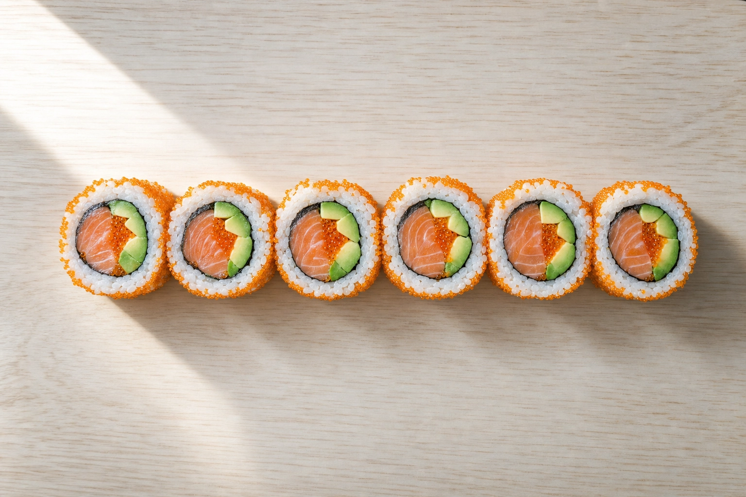 Top-down view of an uramaki sushi roll cut into pieces showing colorful rice, nori and filling cross-sections