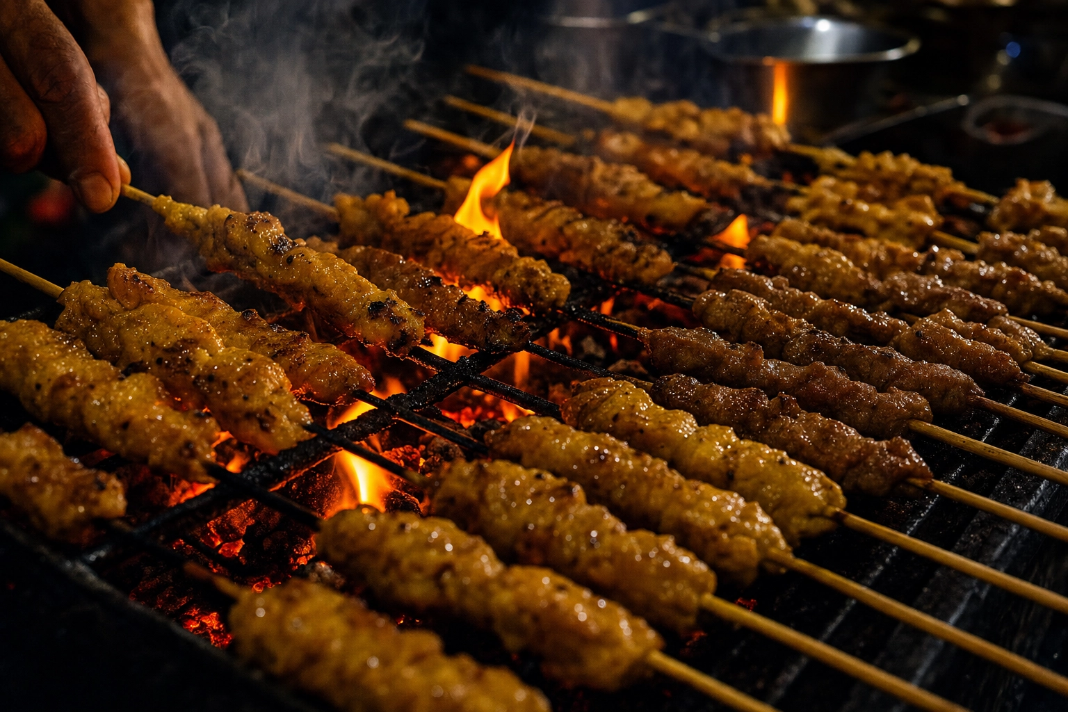 Thai satay and moo ping skewers grilling over glowing charcoal with smoke and char at a night street stall