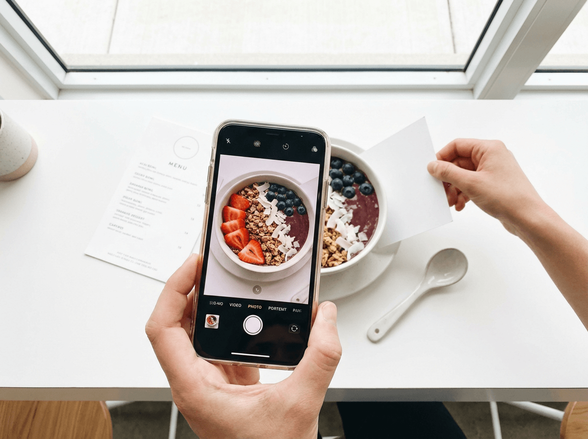 Smartphone capturing overhead photo of colorful acai bowl for Uber Eats upload with natural lighting