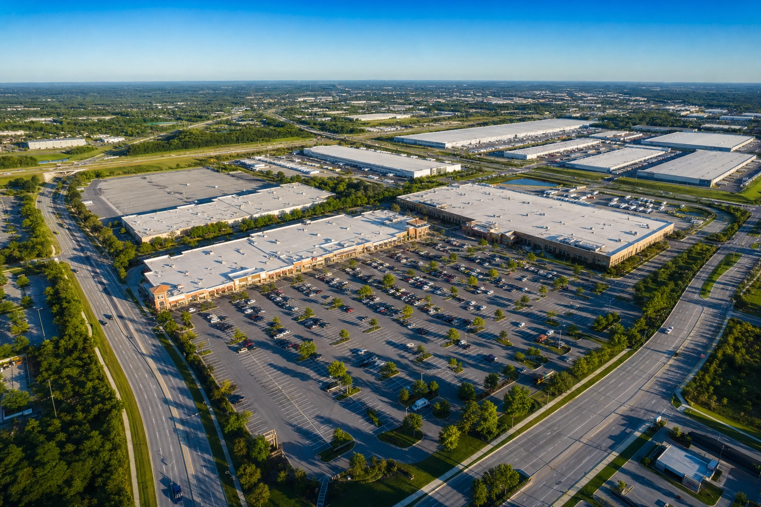 Aerial drone view of a commercial retail center and logistics park showing parking, rooftops and truck court