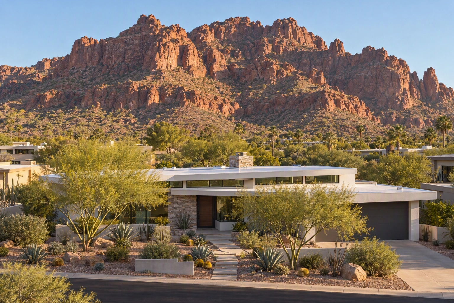 Telephoto 70mm drone photo compressing a mid-century desert ranch home against a red-rock mountain ridge