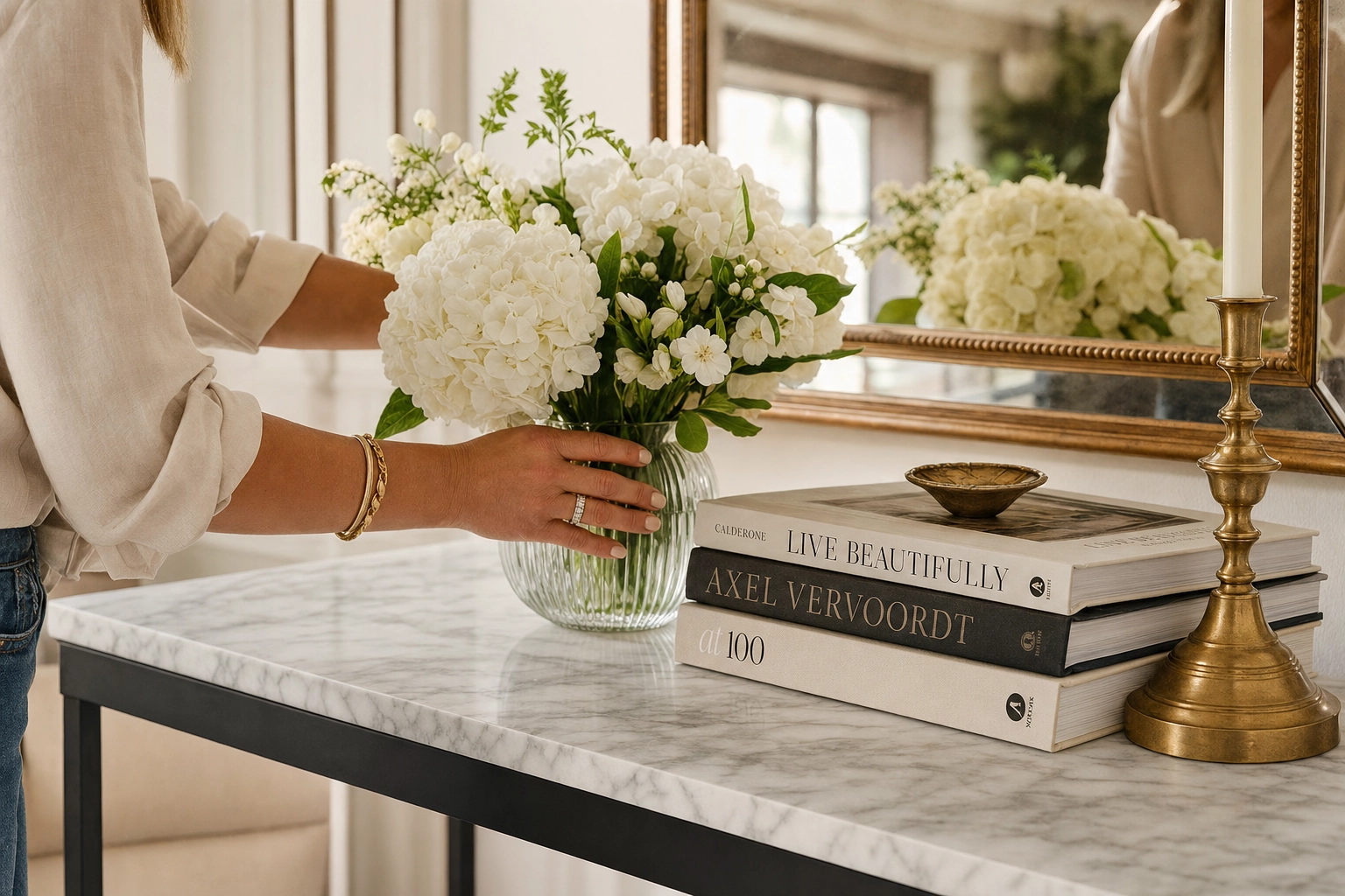 Professional stager's hands styling a console table in a luxury home, showing hands-on real physical staging