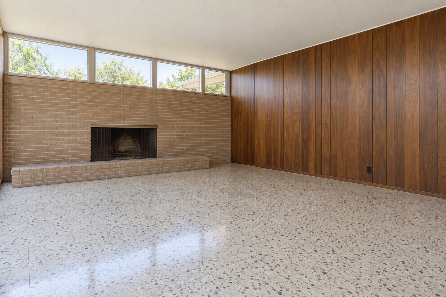 Empty mid-century den with terrazzo floor, walnut paneling and clerestory windows, a vacant room ready for virtual staging