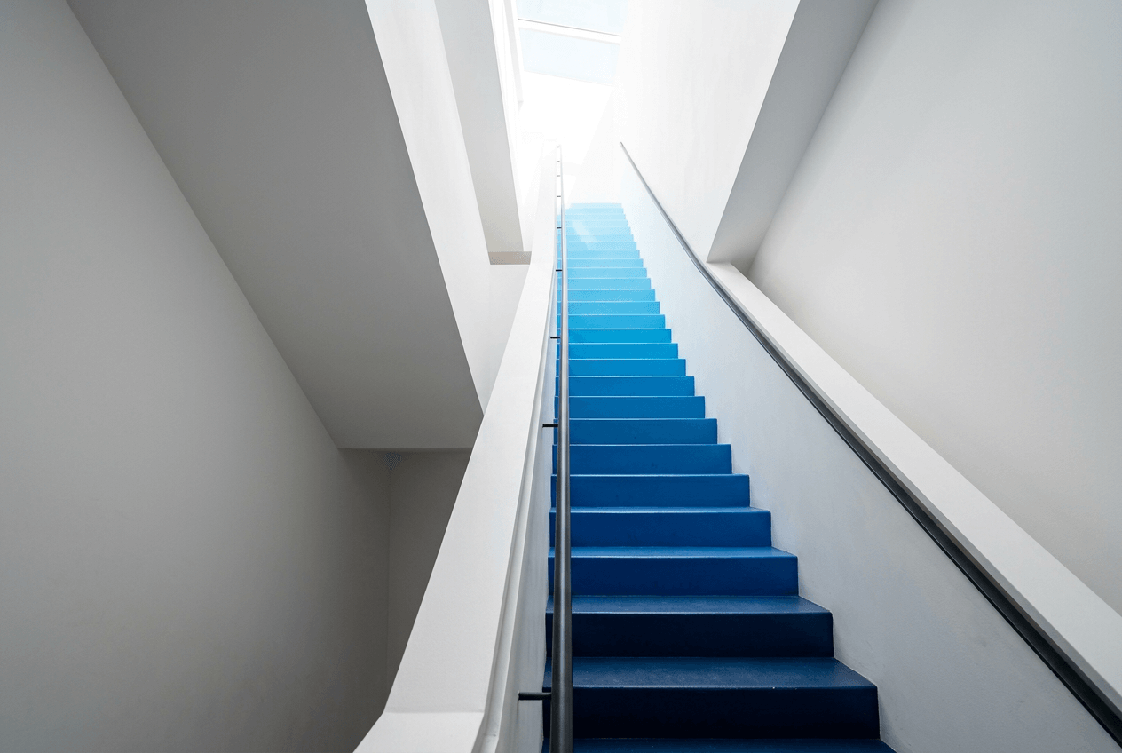 Ascending staircase transitioning from dark to bright blue symbolizing gradual English speaking progress and improvement