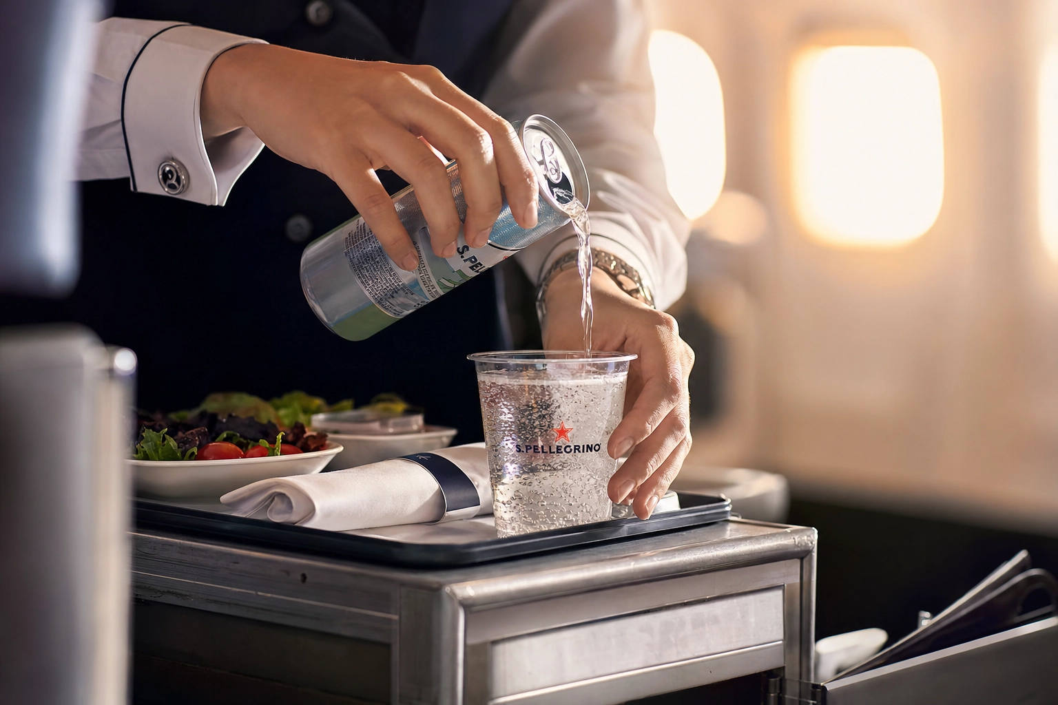 Nahaufnahme einer Flugbegleiterin, die am Servicetrolley während des Bordservice ein Getränk einschenkt