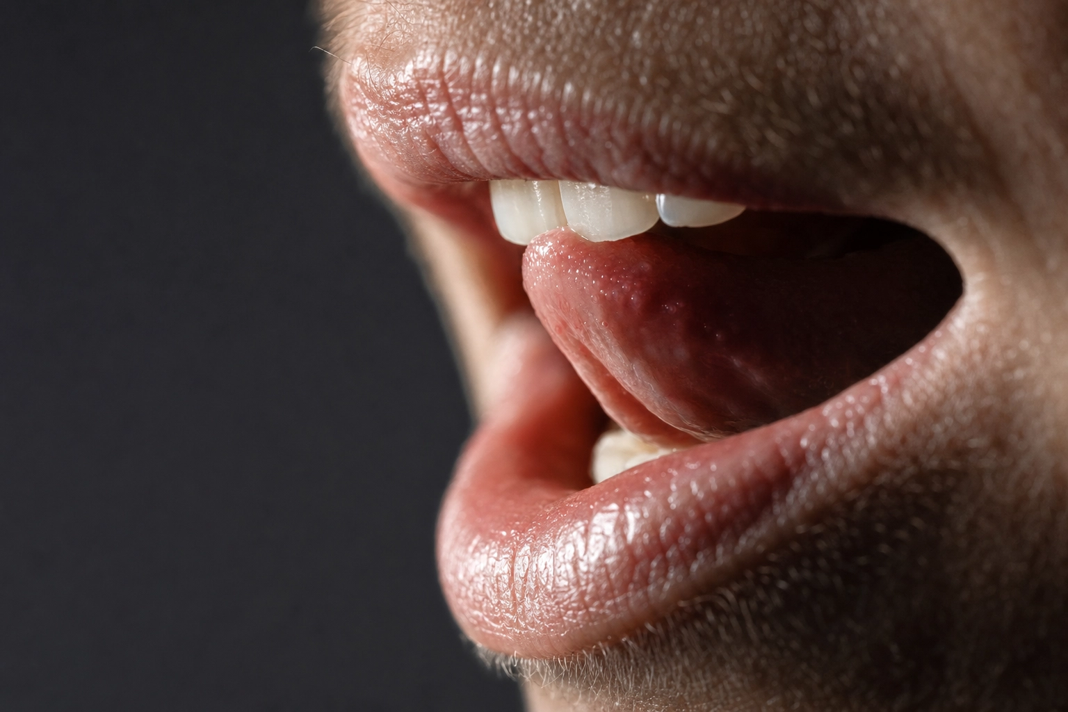 لقطة قريبة لوضعية الفم واللسان وهما يشكّلان صوت TH الإنجليزي الذي يعاني منه الناطقون بالألمانية