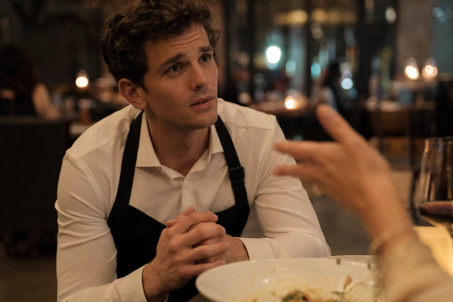 Server kneeling next to a restaurant table listening attentively with empathy to a seated customer's concern