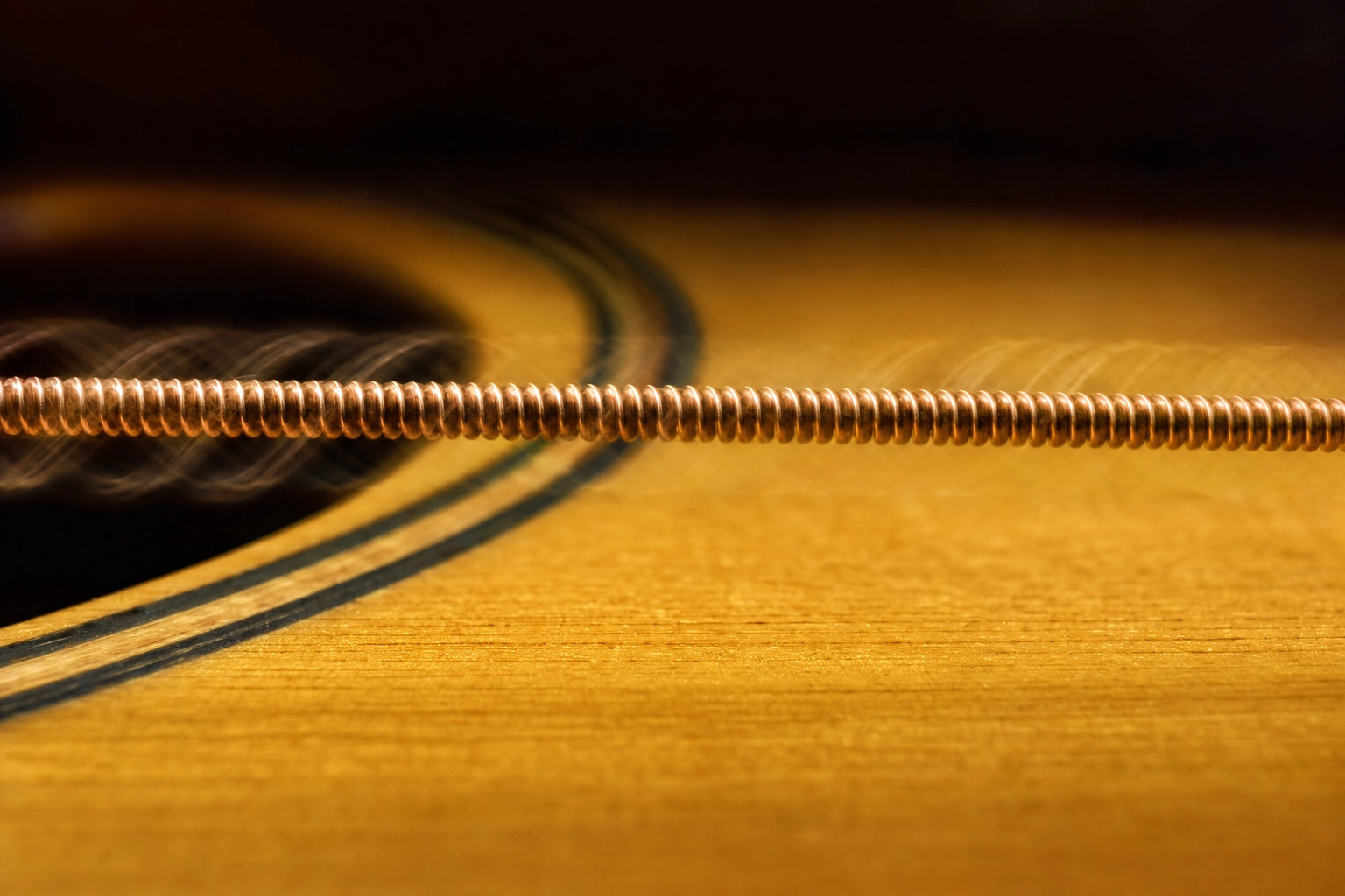 Vibrating guitar string in extreme macro, representing the held single sound of consonant-to-consonant linking in English