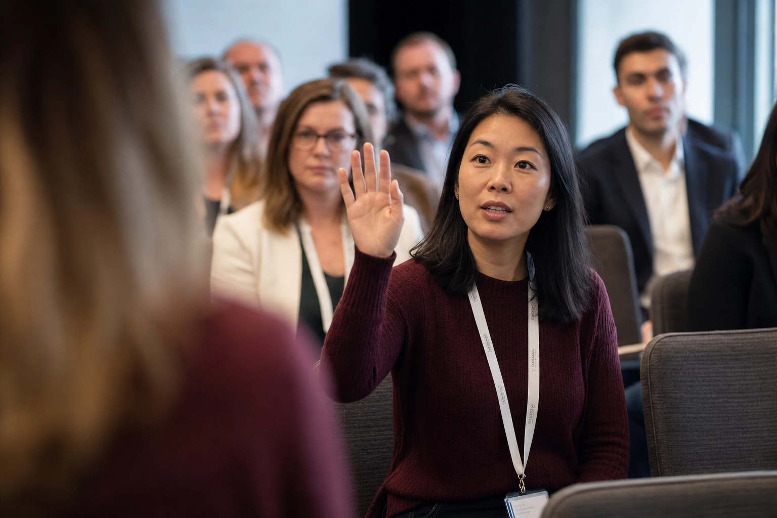 Audience member raising hand to ask question during Q&A session of English presentation in conference room