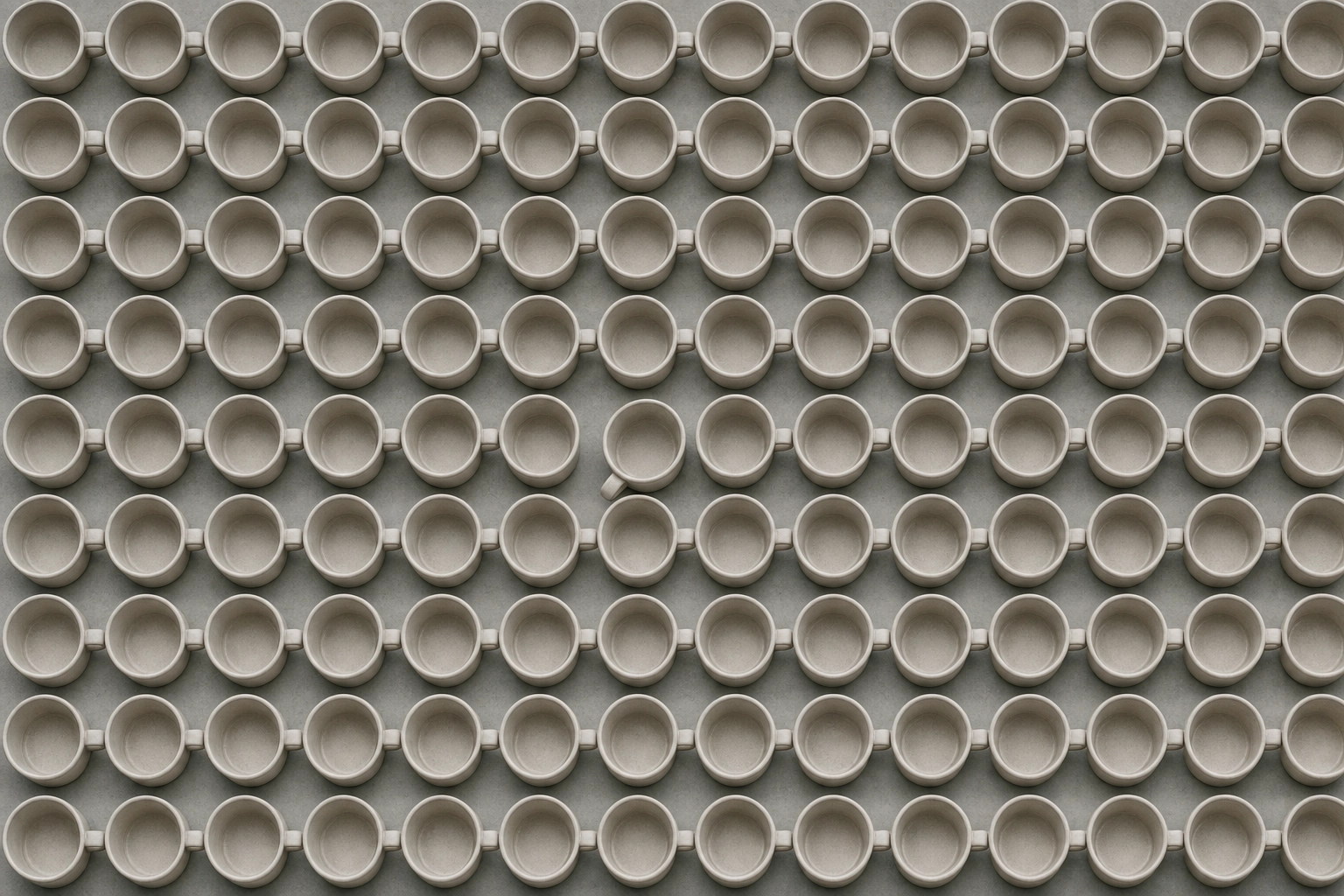 Top-down grid of identical beige cups with one turned aside, symbolizing repetitive, monotonous language drills